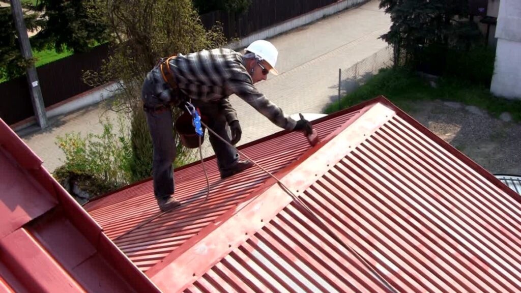 Roofer installing fire-resistant metal roofing as part of a wildfire rebuild project in Los Angeles by R.E.A.L.|cw Architecture.
