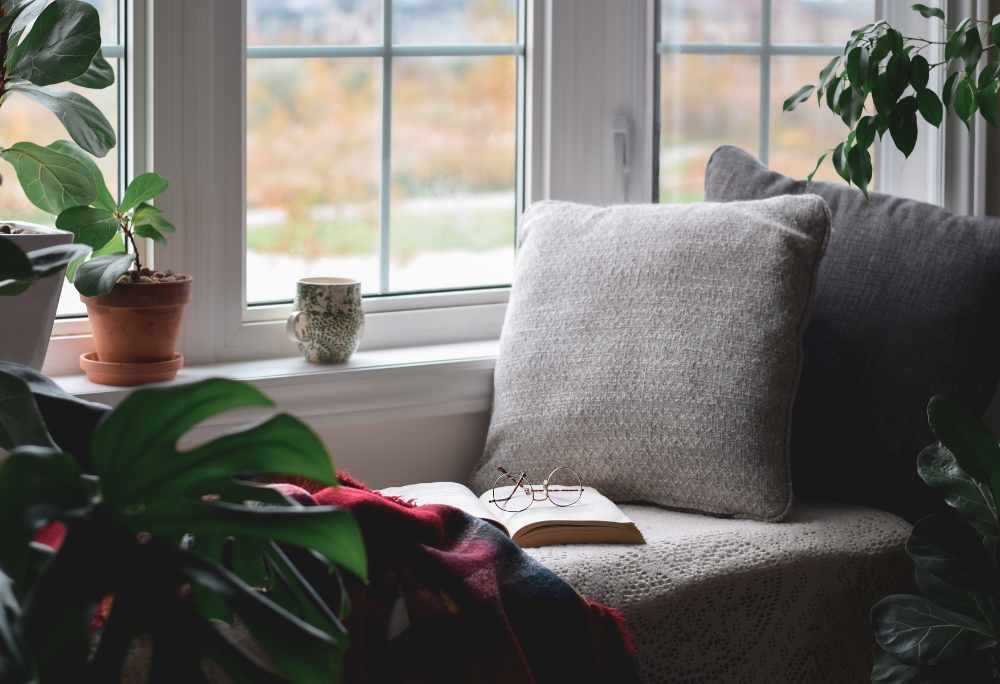 cozy reading nook with natural light, indoor plants, and throw pillows by the window in a Los Angeles home by REAL Arch